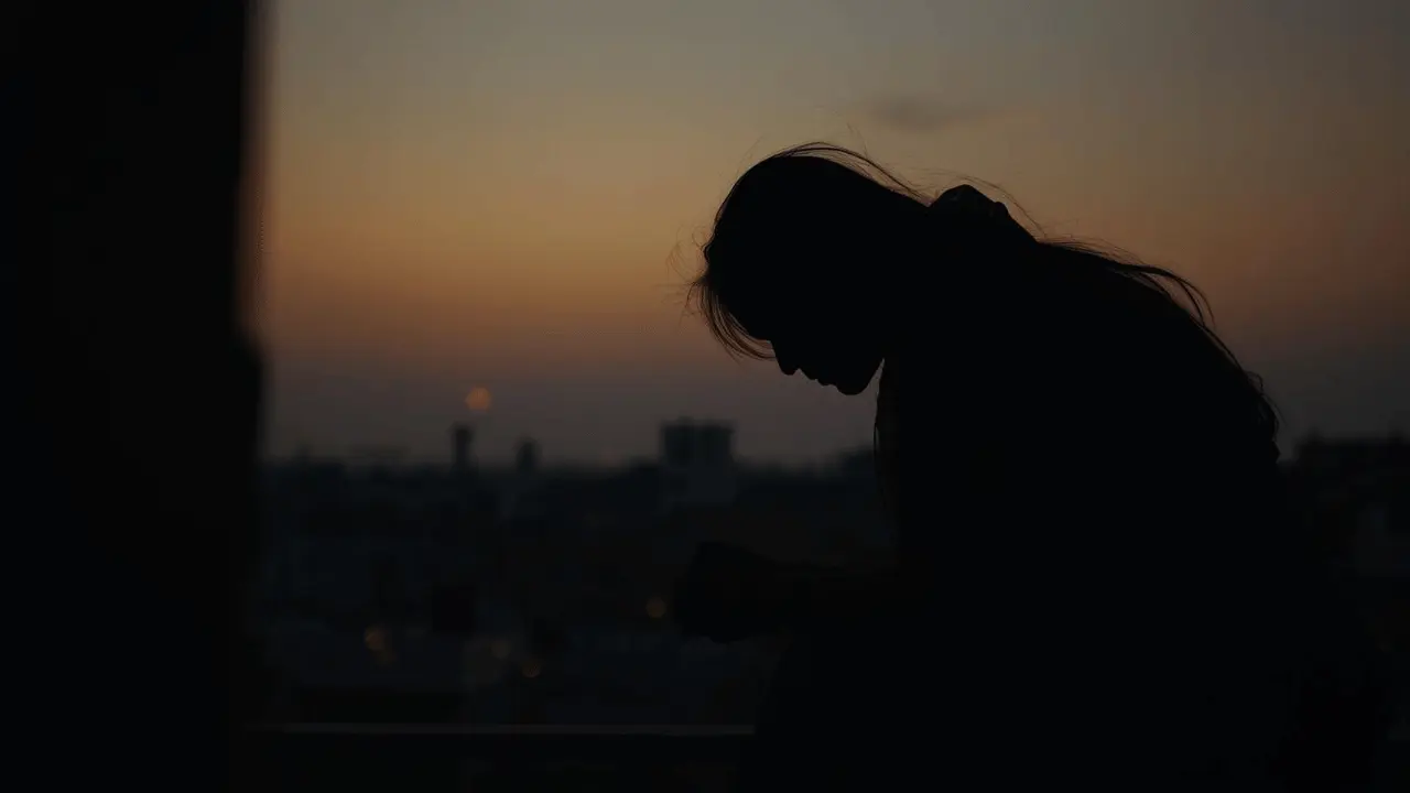 an Indian girl sitting alone on a balcony in Patna during sunset, lost in thought